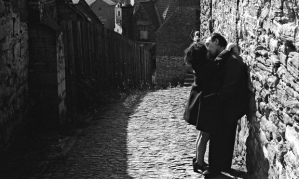 A middle-aged couple kiss in a back alley in Durham.